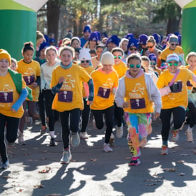 Three Girls on the Run participants smile at the camera while  at the 5K in purple team shirts